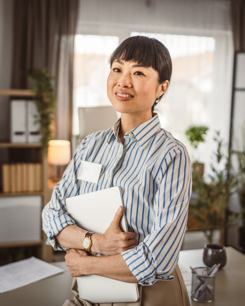 日本成熟女性在办公室拿着笔记本电脑的照片图片下载