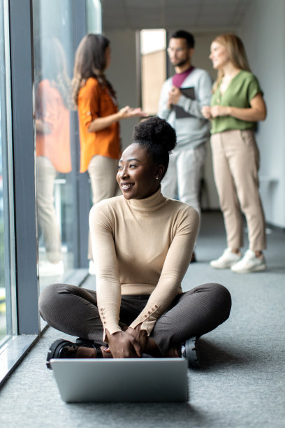 年轻漂亮的女商人在办公室用笔记本电脑工作，坐在地板上图片下载
