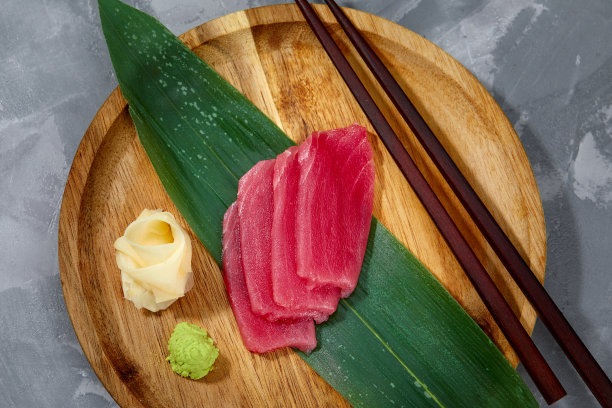 从上面看，金枪鱼片放在竹叶上，生姜和芥末被切碎，准备寿司。图片下载