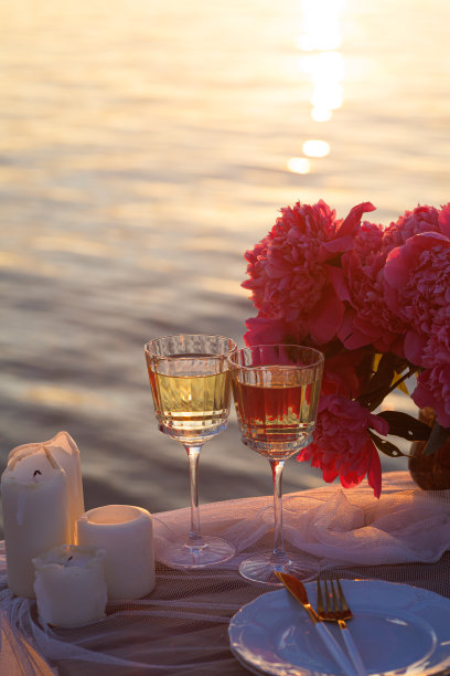 海滩上浪漫的日落晚餐。餐桌蜜月二人组与豪华的食物，一杯香槟饮料在餐厅与海景。夏日恋爱，浪漫约会就在度假概念上。图片下载