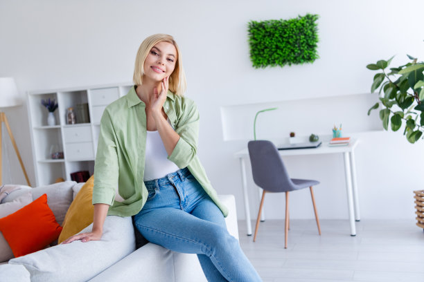 可爱可爱的漂亮女士坐在沙发上，在她舒适的工作空间白色现代室内的照片图片下载