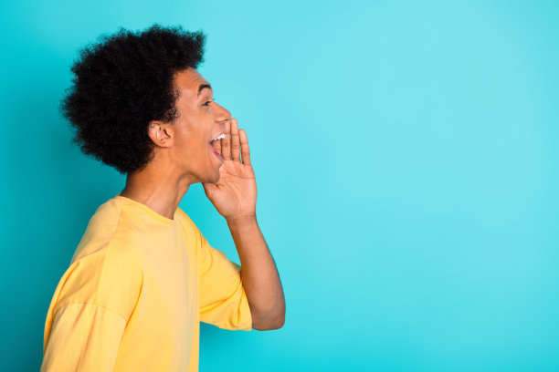 侧面资料照片欣喜若狂的家伙与非洲发型穿着t恤手臂在脸颊大喊在空旷的空间孤立的绿松石色背景图片下载