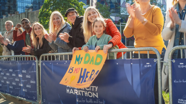 白天，一群不同的人在城市里跑马拉松。家庭成员的支持:小女孩和她的妈妈在观众中为她的爸爸欢呼图片下载