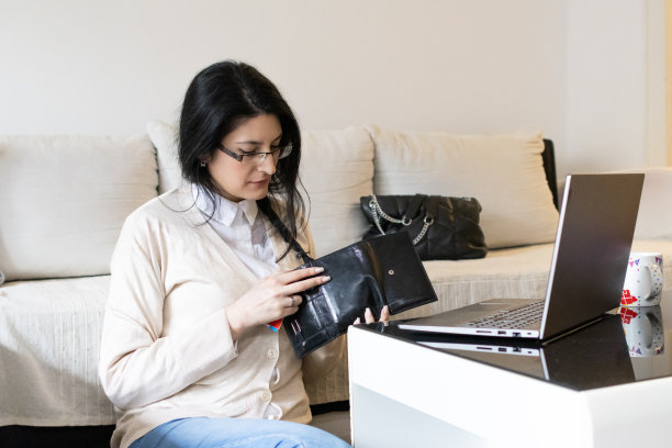 一个漂亮的年轻女子用信用卡网购的照片。她正在客厅的笔记本电脑上使用网上银行服务。图片下载