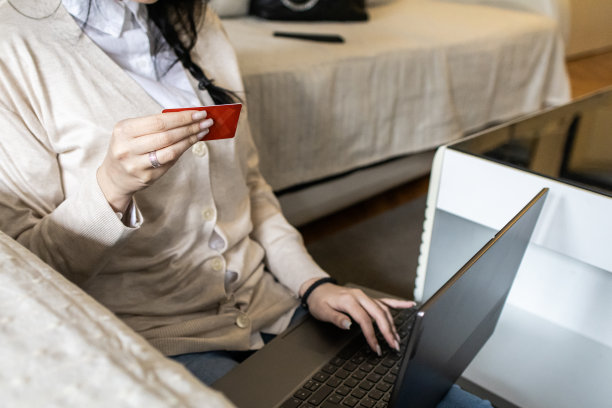 一个漂亮的年轻女子用信用卡网购的照片。她正在客厅的笔记本电脑上使用网上银行服务。图片下载