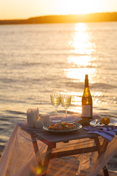 海滩上浪漫的日落晚餐。餐桌蜜月二人组与豪华的食物，一杯香槟饮料在餐厅与海景。夏日恋爱，浪漫约会就在度假概念上。图片下载