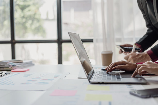 商人和女商人正在开工作会议，桌上放着许多财务文件。办公室里忙着进行商业利润分析和头脑风暴。特写照片图片下载