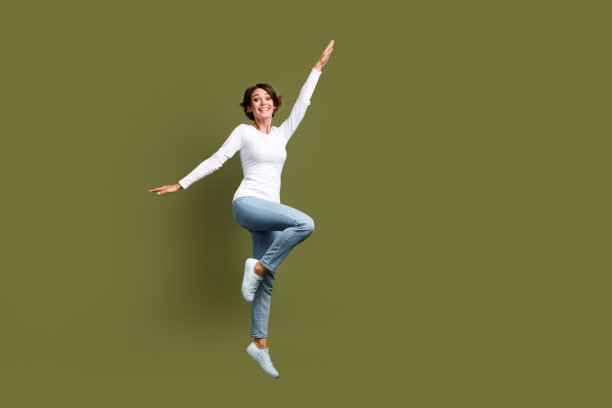 漂亮的年轻女孩的全身照片举起手跳有乐趣穿着时尚的白色服装孤立的卡其色背景图片下载