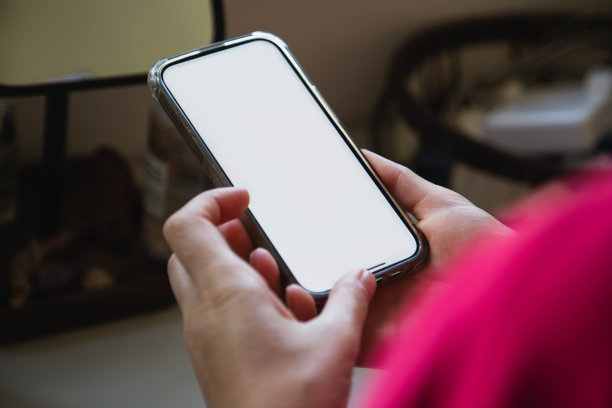 漂亮的女孩在办公室里手里拿着智能手机图片下载