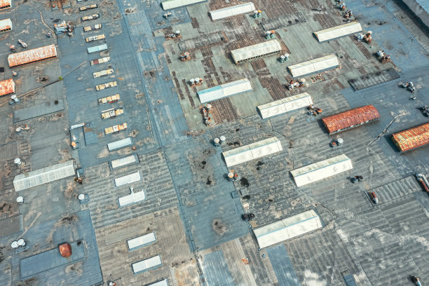一座老工业建筑的屋顶鸟瞰图，上面有通风设备和天窗。无人驾驶飞机的照片。图片下载