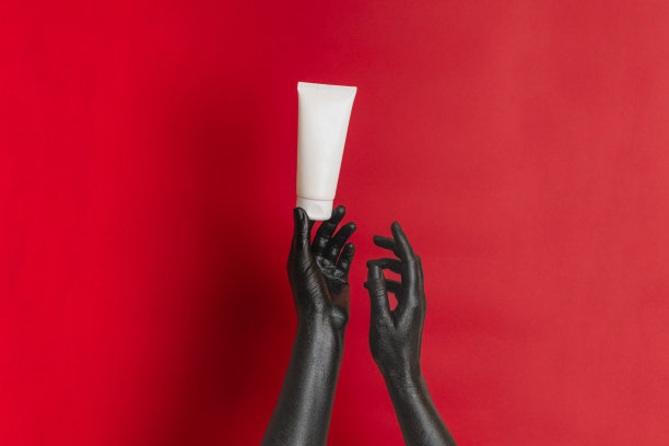 黑色优雅的手涂在她的皮肤上，用润肤霜化妆空白管。奢侈品化妆品广告。图片为您的设计图片下载