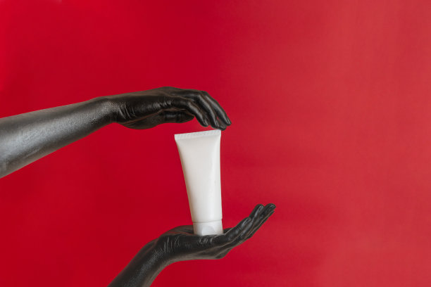 黑色优雅的手涂在她的皮肤上，用润肤霜化妆空白管。奢侈品化妆品广告。图片为您的设计图片下载