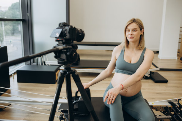 体育博客。一位美丽的孕妇在运动时用相机拍下了她的锻炼过程。视频。怀孕期间的健康和运动。高质量照片图片下载