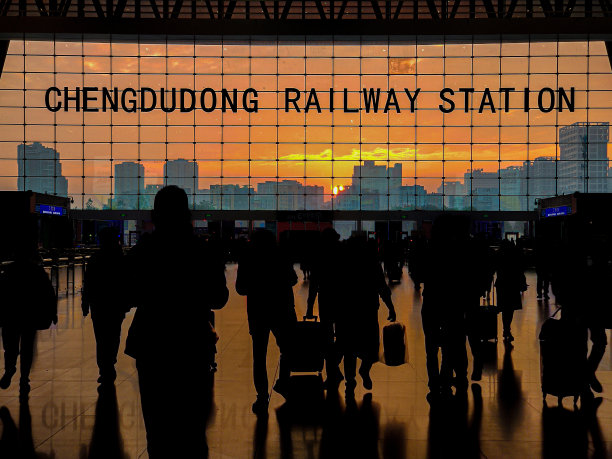 成都东站的日出，旅客的剪影，背景中的城市天际线——中国四川成都图片下载