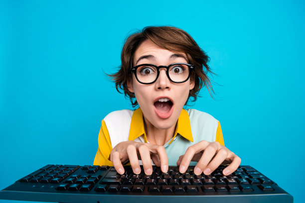 照片惊讶的营销女士在电脑上工作的电脑印象深刻的写html代码孤立的蓝色背景图片下载