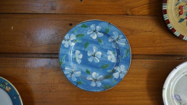 挂在木墙上，蓝边饰有白花画的蓝色装饰板图片下载