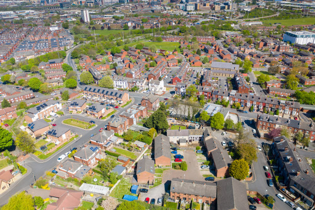 在春天拍摄的利兹西约克郡比斯顿村的航拍照片，显示了一个典型的英国公园，旁边是20世纪40年代的排屋、道路和街道图片下载