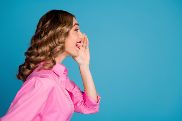 漂亮的年轻女孩的照片肖像简介分享秘密穿着时髦的粉红色服装发型孤立的蓝色背景图片下载