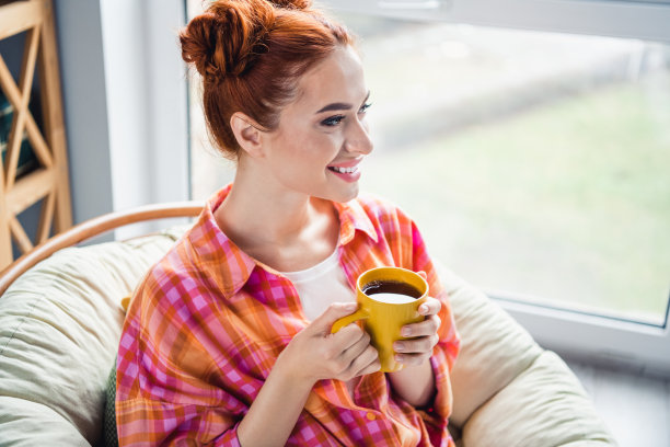 宁静可爱女孩的照片，牙齿微笑，拿着新鲜的咖啡杯，看着窗户，想象，幻想，花消遣房子里面图片下载