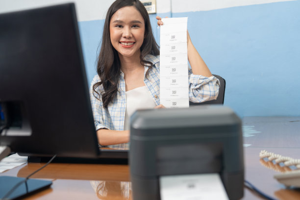 亚洲妇女使用个人电脑在条码打印机上打印条码贴纸图片下载