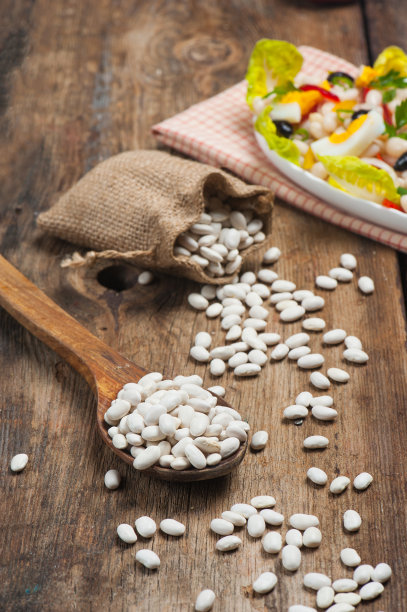 高角度的照片，一个传统的勺子，充满了传统的土耳其海军豆子和洋葱在橄榄油中称为菜称为piyaz在老式木桌的背景图片下载