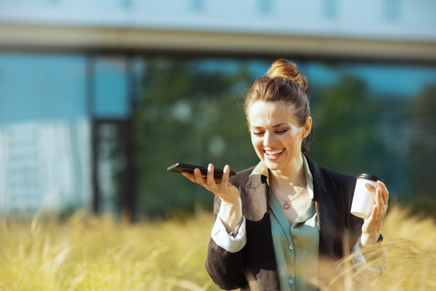 在商务中心附近使用智能手机的微笑女工图片下载