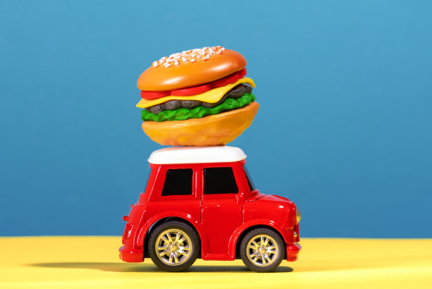 蓝色和黄色背景的车顶上有一辆红色小车，上面装着汉堡。图片下载
