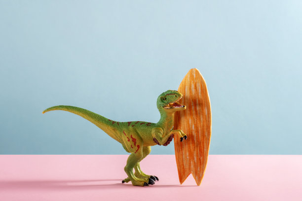 快乐的恐龙与冲浪板在粉红色和蓝色的背景。图片下载