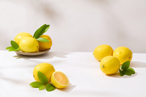 新鲜的黄柠檬整齐地摆放在白色的桌子上，空白的空间用来展示天然成分的产品。广告或设计的正面照片图片下载