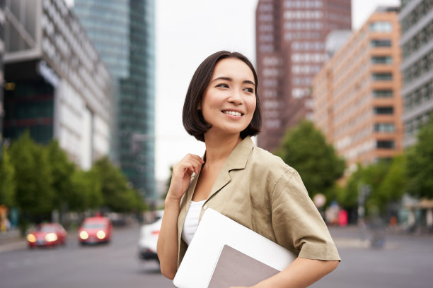 亚洲女孩带着笔记本电脑的户外照片，在市中心的某个地方，走在街上，去上班图片下载