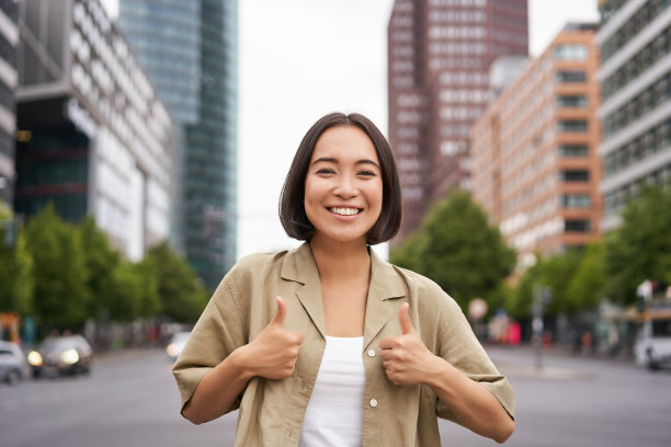 热情的城市女孩，竖起大拇指表示赞同，看起来很乐观，说“是”、“赞成”和“同意”，站在街上图片下载
