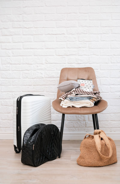 旅行袋，旅行箱，女士衣服在椅子上准备旅行在明亮的客厅。图片下载