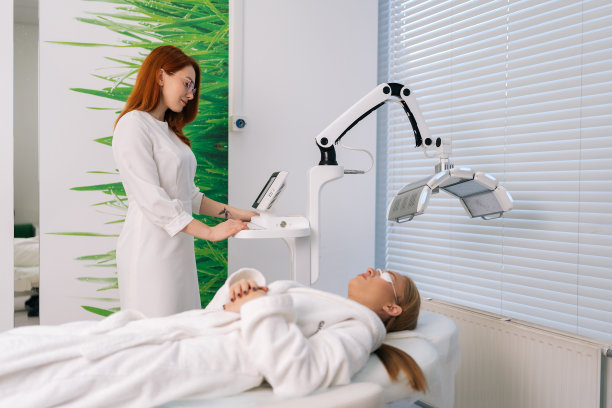 专业女美容师专业现代美容诊所照片剥离连接调节装置。接受LED光动力面部治疗的女性图片下载