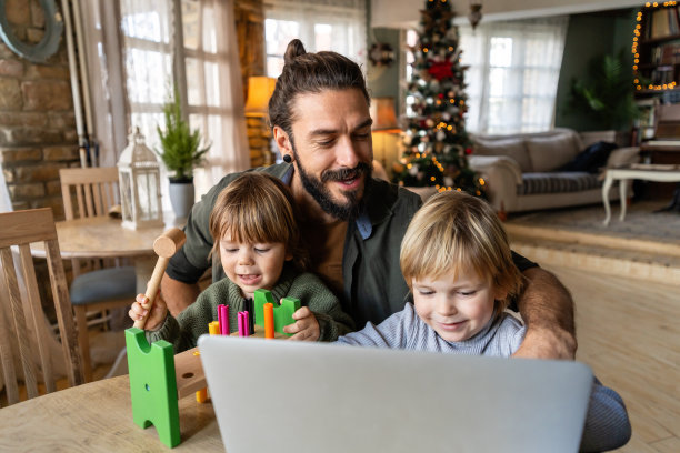 父亲身份和远程业务。快乐的单身爸爸在家工作，孩子们在他身边玩耍图片下载