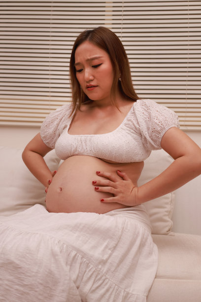 在怀孕期间尽情享受牛奶的好处，这张可爱的亚洲女性在客厅放松的照片。她手里端着一杯牛奶，流露出喜悦和满足的神情。图片下载