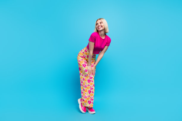 迷人的年轻女子的全身照片，少女造型的模特穿着时尚的粉红色衣服，孤立在蓝色的背景图片下载