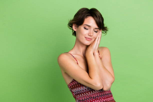 梦幻可爱的漂亮女孩的照片，穿着时髦的衣服，手臂触摸脸，享受睡眠的空白空间，孤立的绿色背景图片下载