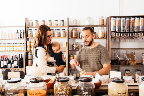 一男一女抱着孩子在零废物杂货店的柜台前图片下载