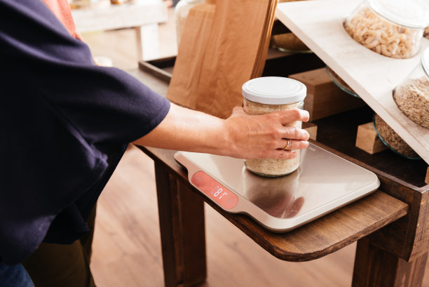 一名妇女在杂货店用电子秤称一罐大米的重量图片下载