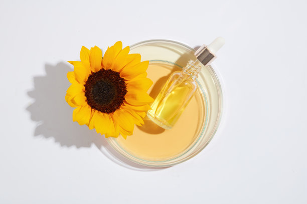 空白标签血清瓶上的特色玻璃培养皿与黄色液体，由向日葵装饰。顶部的照片与空白的空间设计图片下载