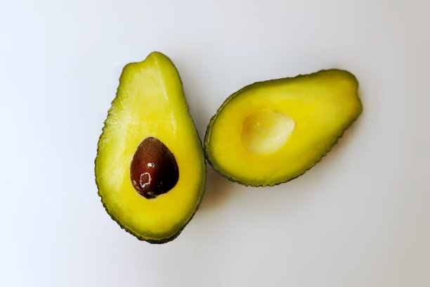 牛油果切成两半，孤立在白色背景上。切削路径。一张明亮、丰富的牛油果横截面照片，里面有一颗种子。图片下载