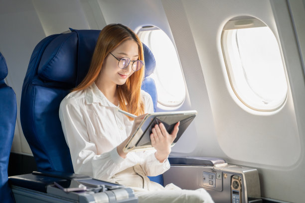 商务女性在飞机上使用平板电脑和手机工作图片下载