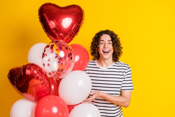 漂亮的年轻人的照片心形气球穿条纹t恤孤立的黄色背景图片下载