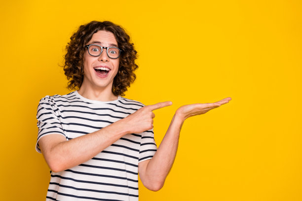 照片肖像漂亮的青少年男性手掌握点兴奋的空间穿时髦的条纹装孤立在黄色的背景图片下载