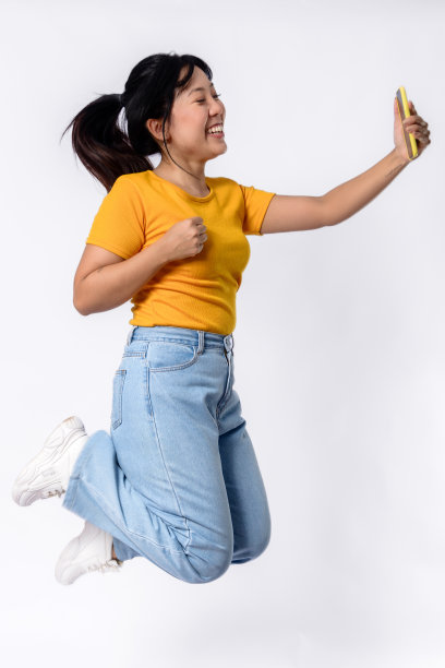 美丽的亚洲女子在摄影棚里用手机自拍图片下载