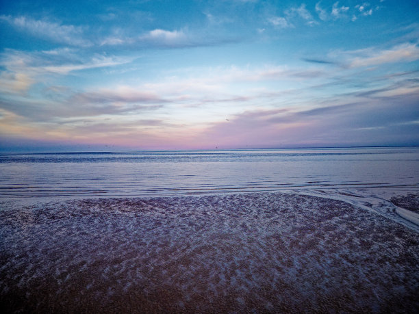 海岸日落场景。航拍照片显示潮汐通道流经沙丘。林肯郡海岸，直布罗陀角。夏日黄昏日落图片下载