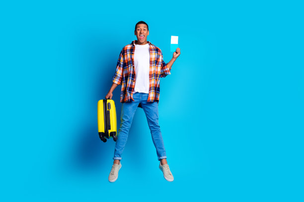 漂亮的年轻人的全尺寸照片行李箱护照跳空空间穿衬衫孤立的蓝色背景图片下载