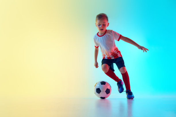 一个穿着足球装备的男孩的运动照片，在渐变背景下的霓虹灯下，他有力的一脚被定格在动作的瞬间。图片下载