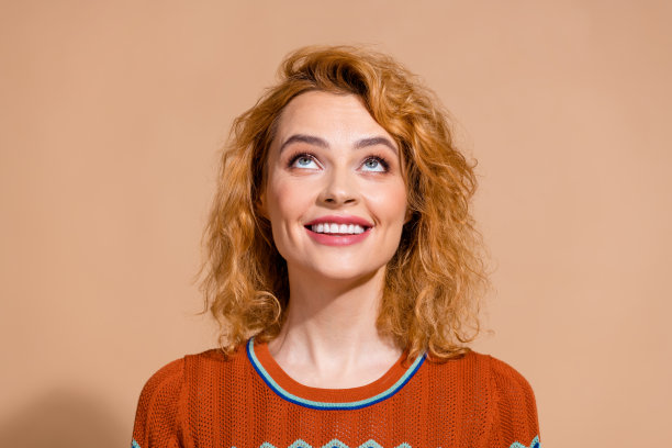 照片乐观的女人波浪发型穿着装饰t恤抬头看标志空白空间孤立在柔和的颜色背景图片下载