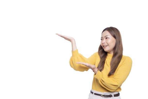 年轻的亚洲女子穿着长袖毛衣和奶油色的照片，在白色孤立的背景下，在旁边张开双臂，带着幸福和自信的微笑看着它。图片下载